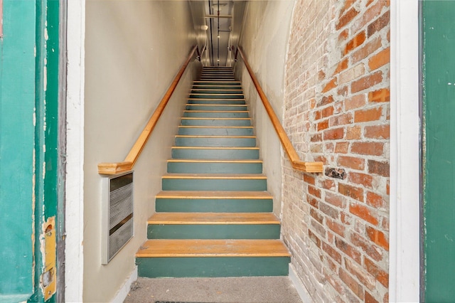 stairway featuring brick wall