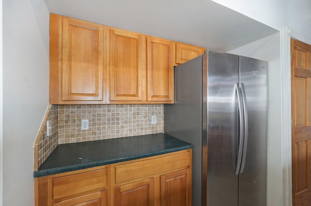 kitchen featuring freestanding refrigerator, dark countertops, and decorative backsplash