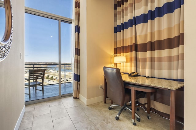 office featuring a water view, a wealth of natural light, light tile patterned floors, and built in desk