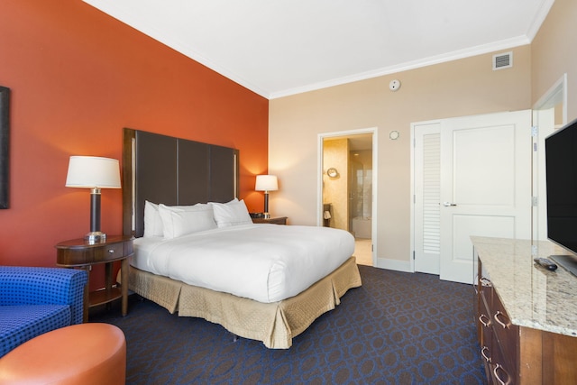 carpeted bedroom featuring crown molding and ensuite bathroom