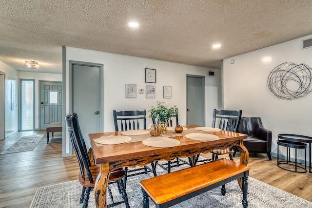 dining area with a textured ceiling and light hardwood / wood-style floors