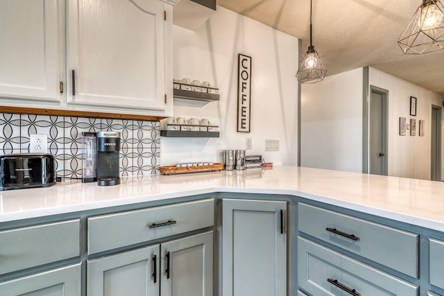 kitchen with a textured ceiling, hanging light fixtures, and tasteful backsplash