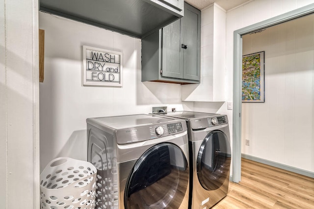 washroom with cabinets, light hardwood / wood-style flooring, and washing machine and clothes dryer