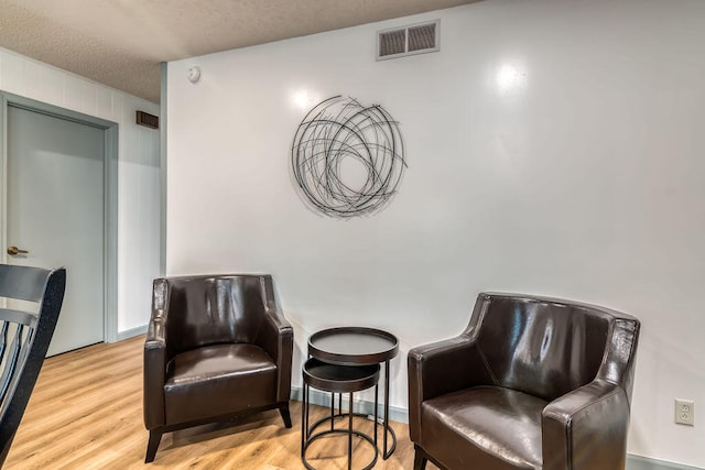 living area featuring a textured ceiling and light hardwood / wood-style flooring