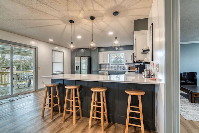 kitchen featuring decorative light fixtures, stainless steel appliances, kitchen peninsula, and decorative backsplash