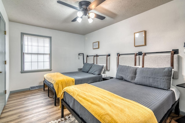 bedroom with wood-type flooring, a textured ceiling, and ceiling fan