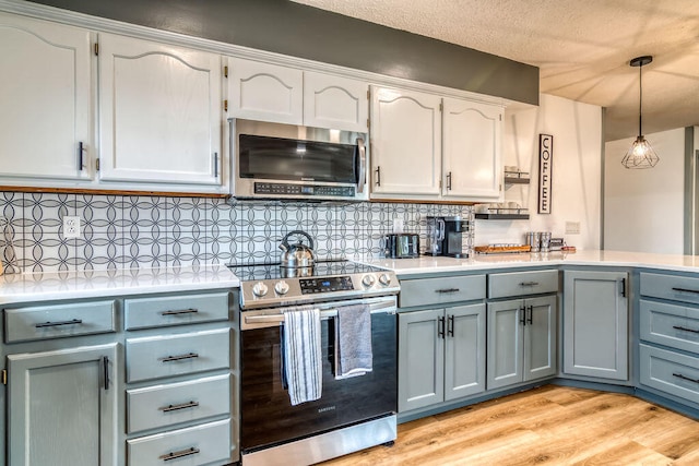 kitchen featuring light hardwood / wood-style floors, decorative backsplash, pendant lighting, stainless steel appliances, and white cabinets