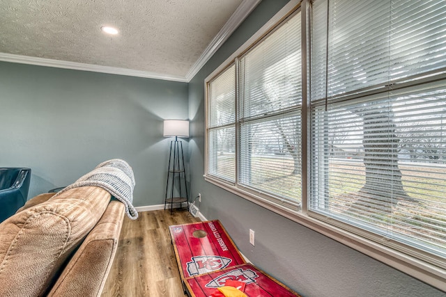 sitting room with ornamental molding, hardwood / wood-style flooring, and a textured ceiling