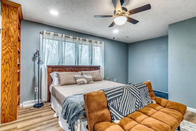 bedroom featuring light hardwood / wood-style floors, a textured ceiling, and ceiling fan