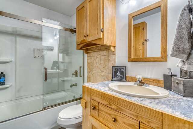 full bathroom with vanity, combined bath / shower with glass door, toilet, and backsplash