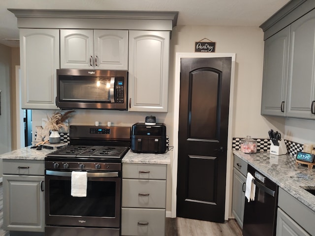 kitchen featuring light stone counters, gray cabinets, stainless steel appliances, and light hardwood / wood-style flooring