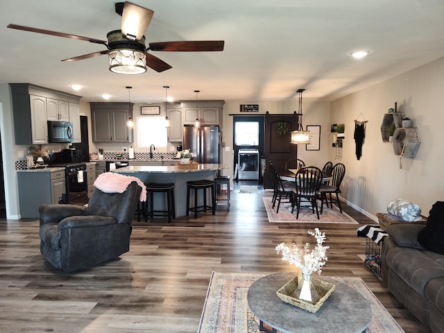 living room featuring dark hardwood / wood-style floors, sink, and ceiling fan