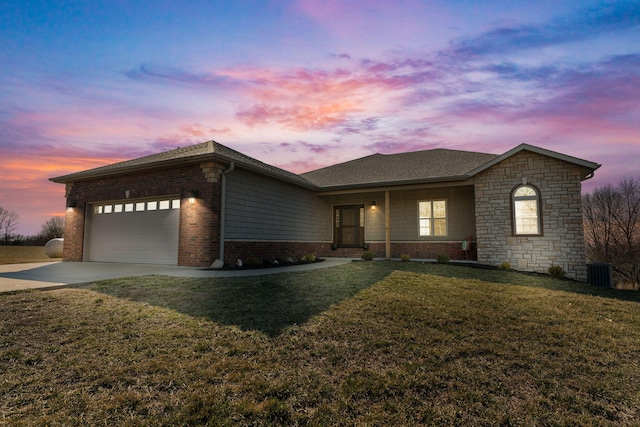 view of front of home with central air condition unit, a lawn, and a garage