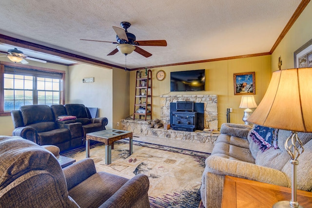 living room featuring a wood stove, crown molding, ceiling fan, and a textured ceiling