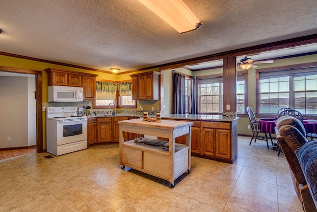 kitchen featuring ceiling fan, a wealth of natural light, white appliances, and a textured ceiling