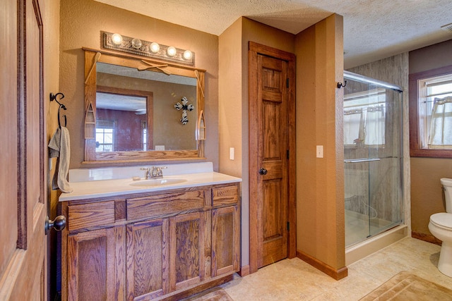 bathroom featuring a healthy amount of sunlight, a shower with shower door, vanity, and toilet