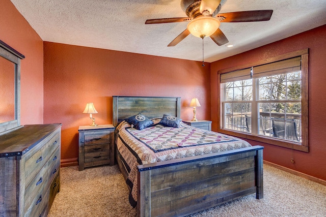 bedroom featuring light colored carpet, a textured ceiling, and ceiling fan