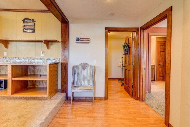 hall featuring light hardwood / wood-style flooring and a textured ceiling