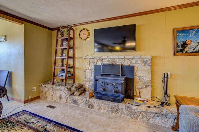 living room with a textured ceiling, ornamental molding, a wood stove, and tile patterned floors