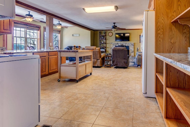 kitchen with range, white fridge, a fireplace, crown molding, and light tile patterned floors