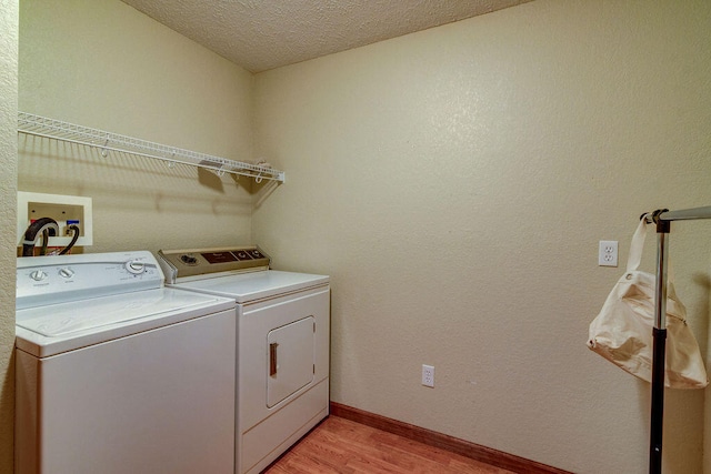 clothes washing area with a textured ceiling, independent washer and dryer, and light hardwood / wood-style flooring