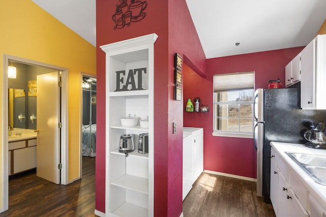 kitchen featuring dark hardwood / wood-style floors, vaulted ceiling, washing machine and dryer, and white cabinetry