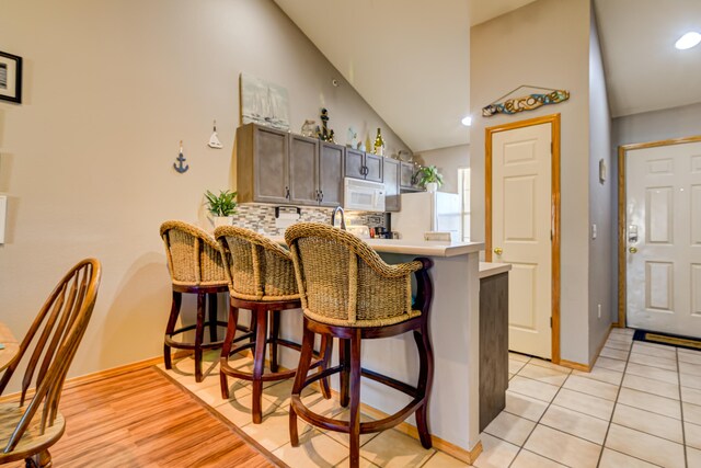 135 Upper Emerald Bay Cir Unit G-13, Hollister, MO 65672 - kitchen featuring tasteful backsplash, a breakfast bar, white appliances, a peninsula, and light countertops