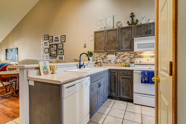 kitchen featuring light hardwood / wood-style floors, white appliances, sink, decorative backsplash, and kitchen peninsula