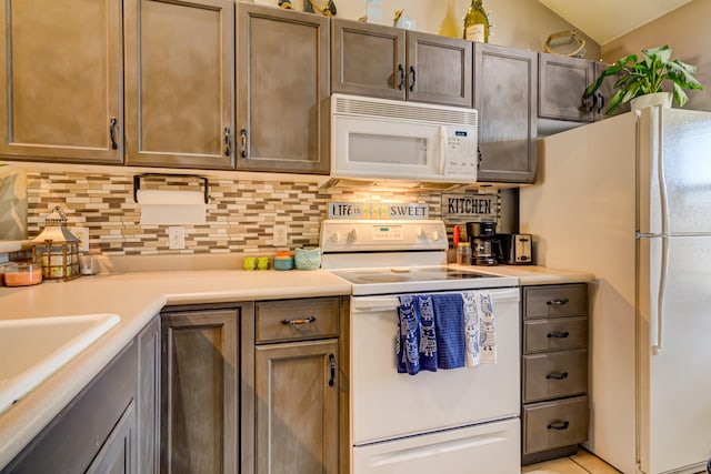 kitchen featuring decorative backsplash, white appliances, and vaulted ceiling