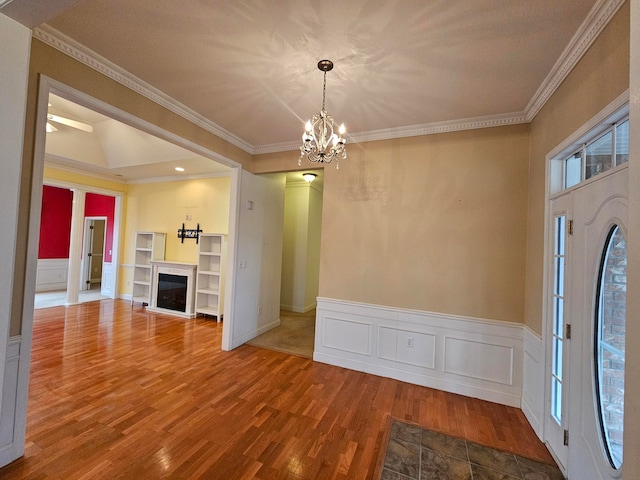 unfurnished living room with crown molding, hardwood / wood-style floors, and a chandelier