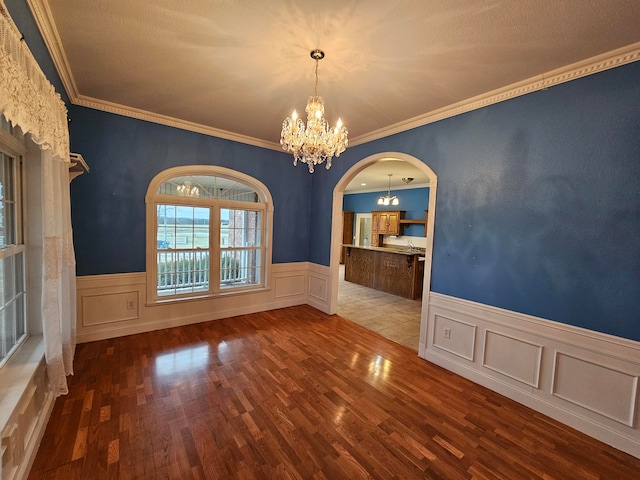 unfurnished dining area with ornamental molding, a notable chandelier, and hardwood / wood-style floors