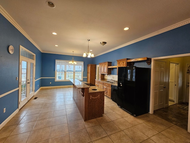 kitchen with crown molding, a kitchen island, decorative light fixtures, a notable chandelier, and black appliances