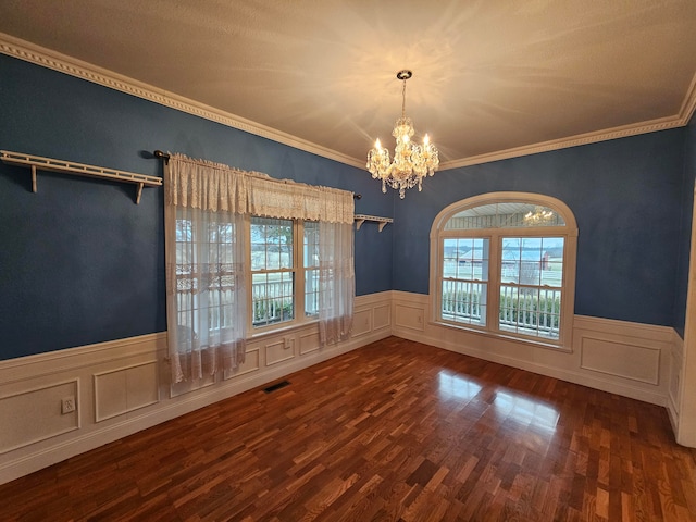 empty room with crown molding, a chandelier, and dark hardwood / wood-style flooring