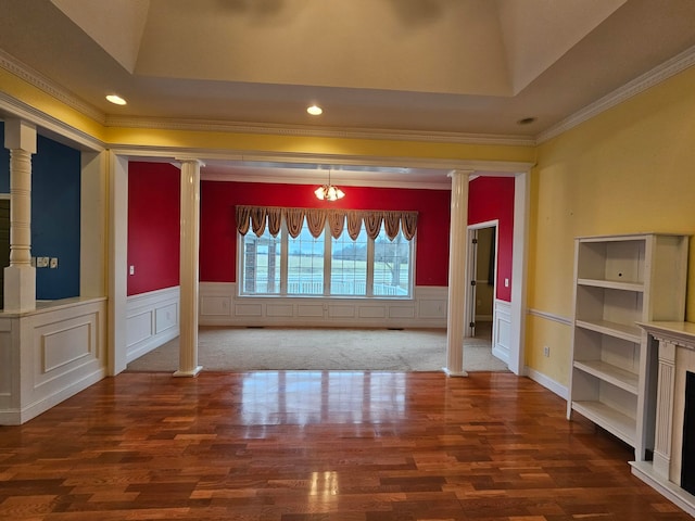 interior space with dark colored carpet, crown molding, a tray ceiling, decorative columns, and built in shelves