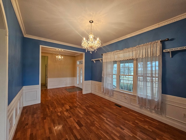 unfurnished room featuring ornamental molding, dark hardwood / wood-style floors, and a chandelier