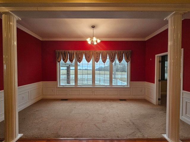 carpeted empty room featuring ornate columns, a water view, a healthy amount of sunlight, and a notable chandelier