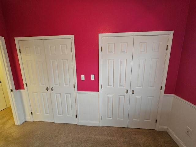 unfurnished bedroom featuring carpet flooring and multiple closets