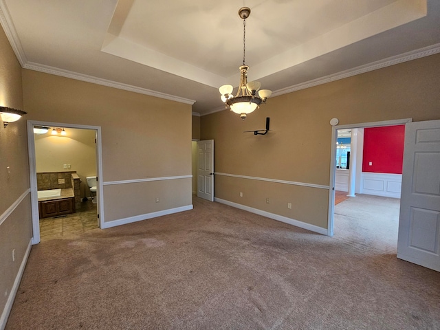 carpeted spare room featuring a notable chandelier, crown molding, and a tray ceiling