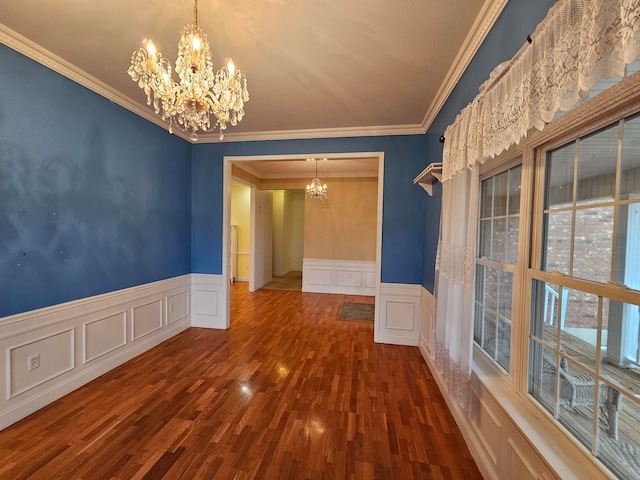 spare room with an inviting chandelier, crown molding, and dark hardwood / wood-style flooring