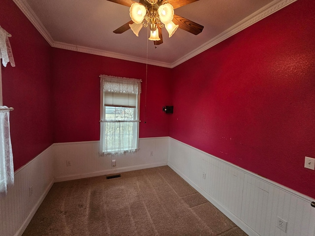 carpeted spare room featuring crown molding and ceiling fan