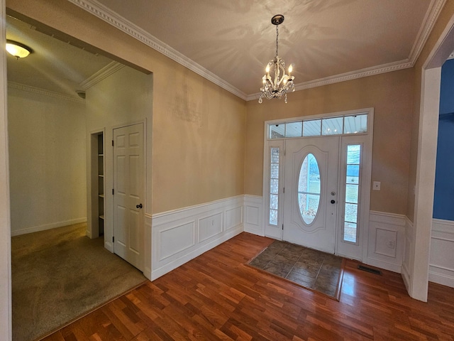 entryway with ornamental molding, an inviting chandelier, and dark wood-type flooring