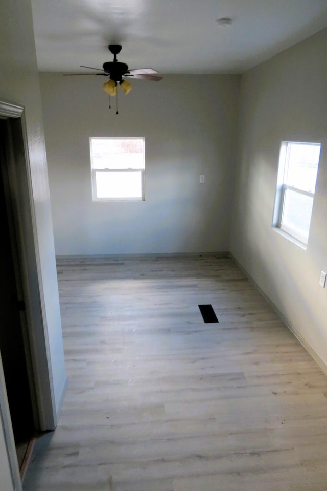 empty room with ceiling fan, light hardwood / wood-style flooring, and a healthy amount of sunlight