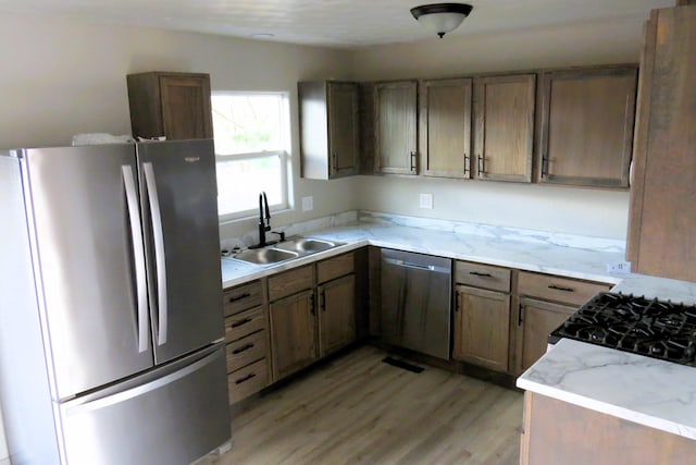 kitchen with appliances with stainless steel finishes, light wood-type flooring, and sink