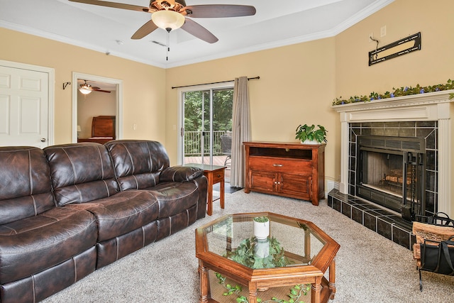 living room with carpet floors, ceiling fan, crown molding, and a tile fireplace