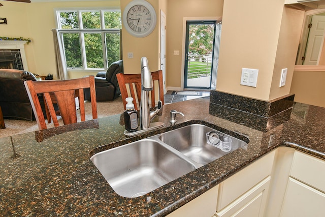 kitchen with carpet, dark stone counters, sink, and white cabinetry