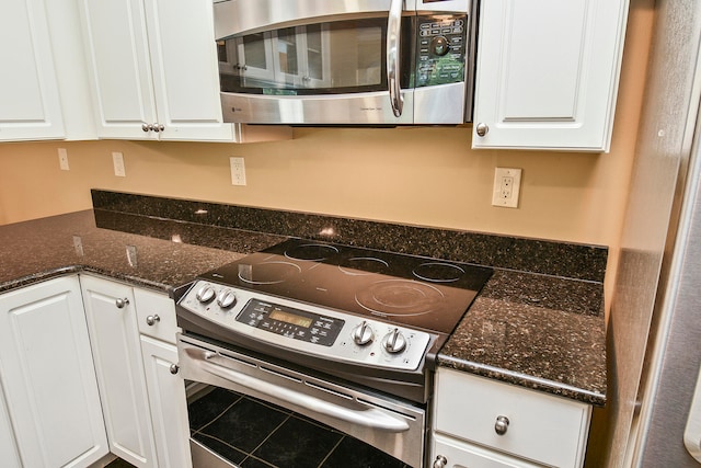 kitchen featuring dark stone counters, tile patterned flooring, white cabinetry, and stainless steel appliances