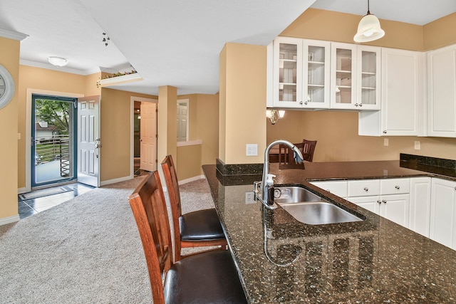 kitchen featuring light carpet, hanging light fixtures, sink, and white cabinets