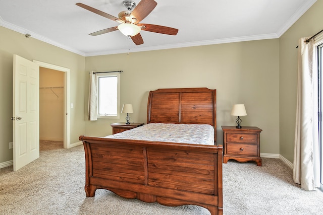 bedroom featuring a walk in closet, ceiling fan, crown molding, light carpet, and a closet