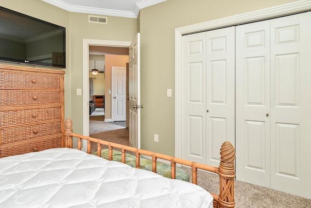 carpeted bedroom with ornamental molding and a closet