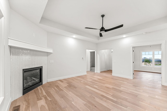 unfurnished living room featuring a fireplace, ceiling fan, and light hardwood / wood-style flooring